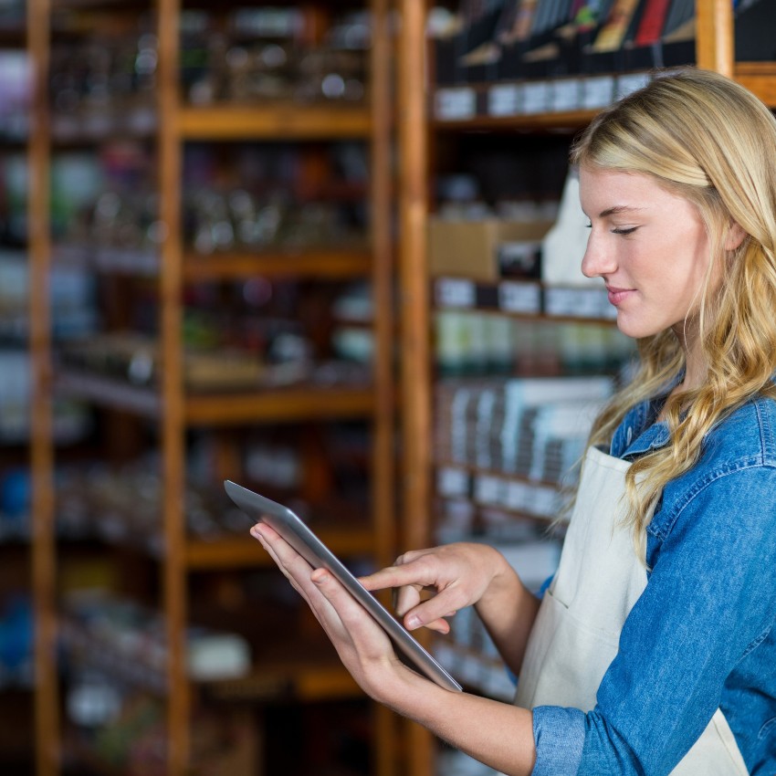 Une employée de magasin consulte sa tablette pour vérifier les stocks disponibles