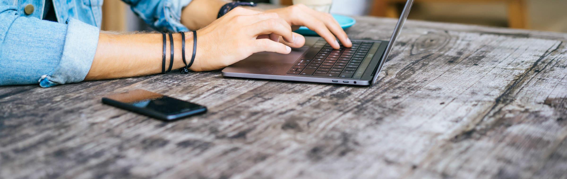 Un homme écrit un document sur son ordinateur portable